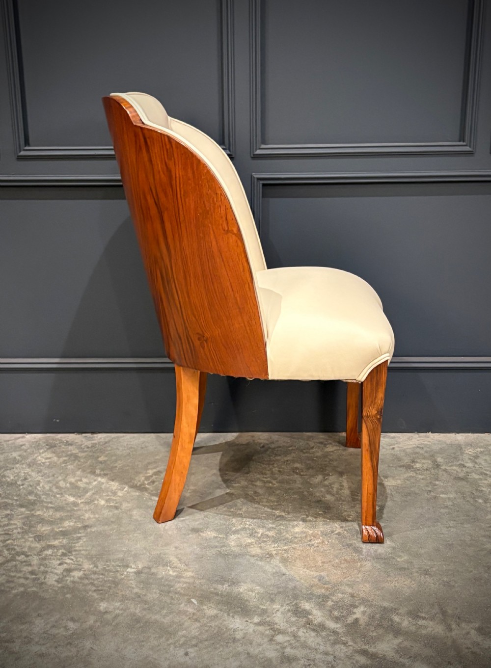 A pair of Art Deco armchairs featuring curved walnut veneer frames and cream leather upholstery. View XII