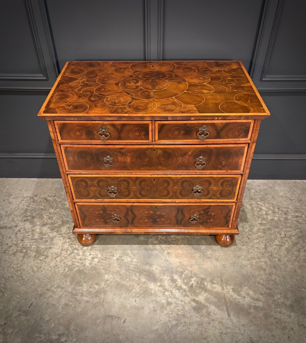 A late 17th-century William and Mary walnut chest of drawers featuring oyster veneered drawer fronts, geometric crossbanding, engraved brass drop handles, and turned bun feet. View III