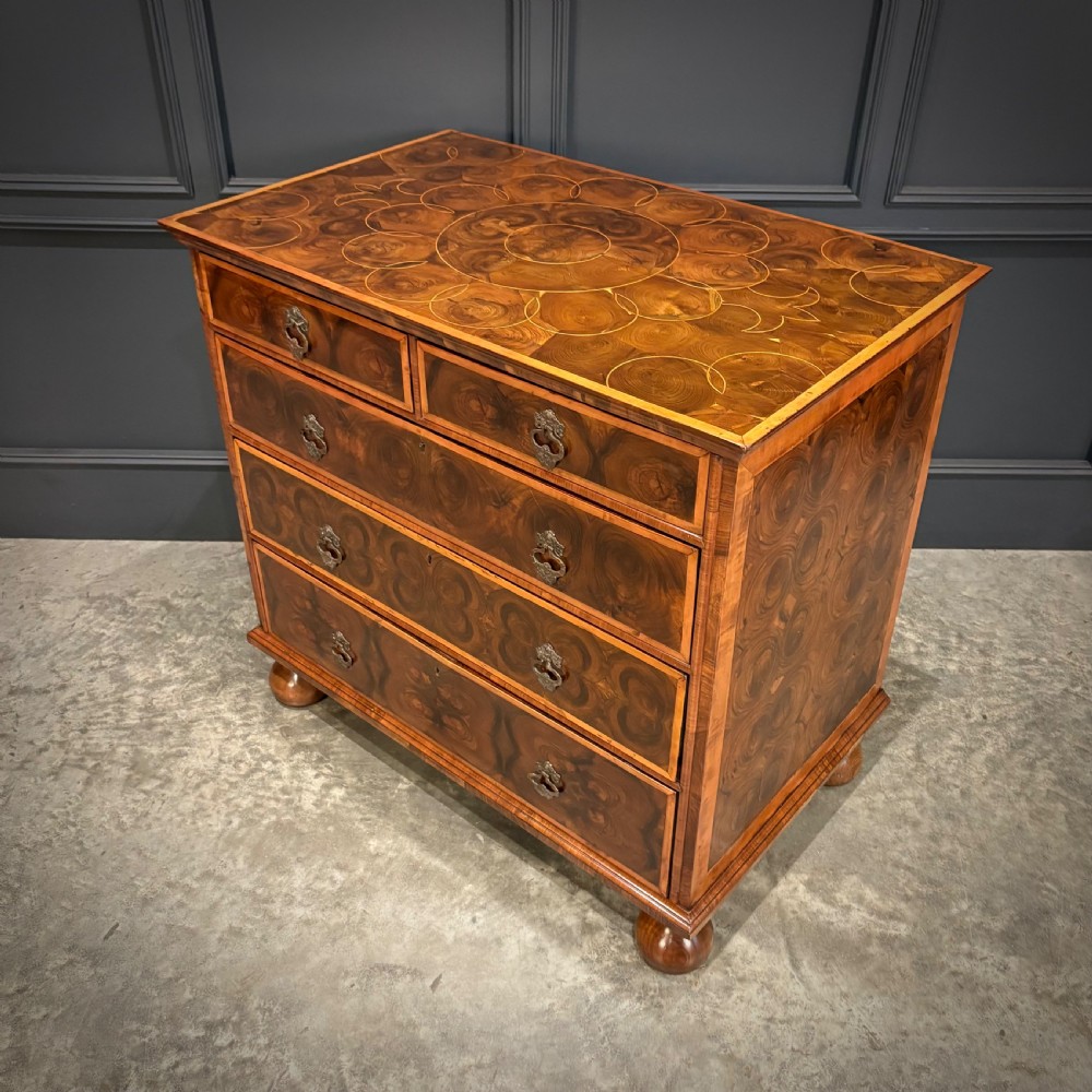 A late 17th-century William and Mary walnut chest of drawers featuring oyster veneered drawer fronts, geometric crossbanding, engraved brass drop handles, and turned bun feet. View VI