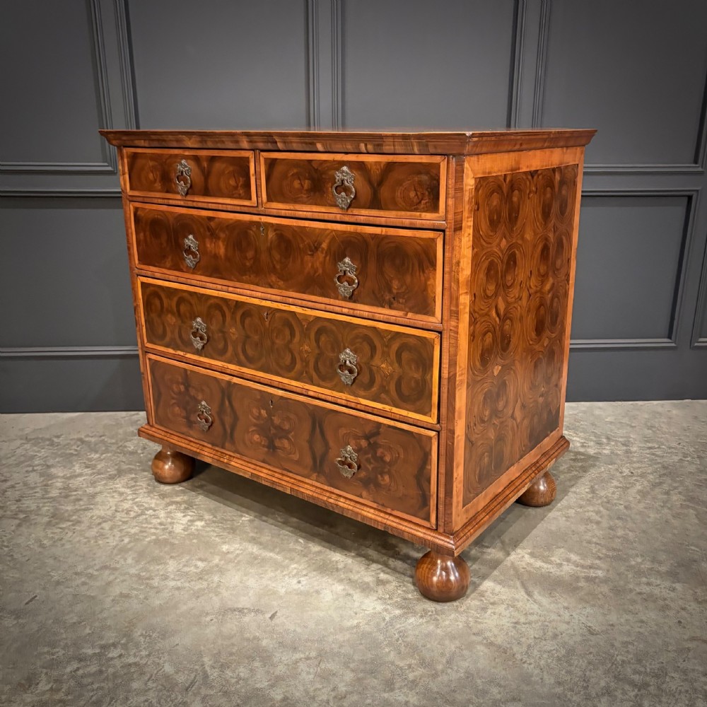 A late 17th-century William and Mary walnut chest of drawers featuring oyster veneered drawer fronts, geometric crossbanding, engraved brass drop handles, and turned bun feet. View VII