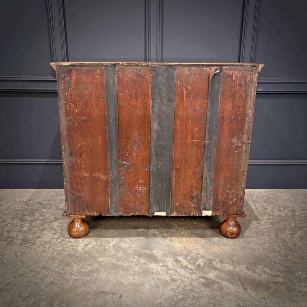 A late 17th-century William and Mary walnut chest of drawers featuring oyster veneered drawer fronts, geometric crossbanding, engraved brass drop handles, and turned bun feet. View IX