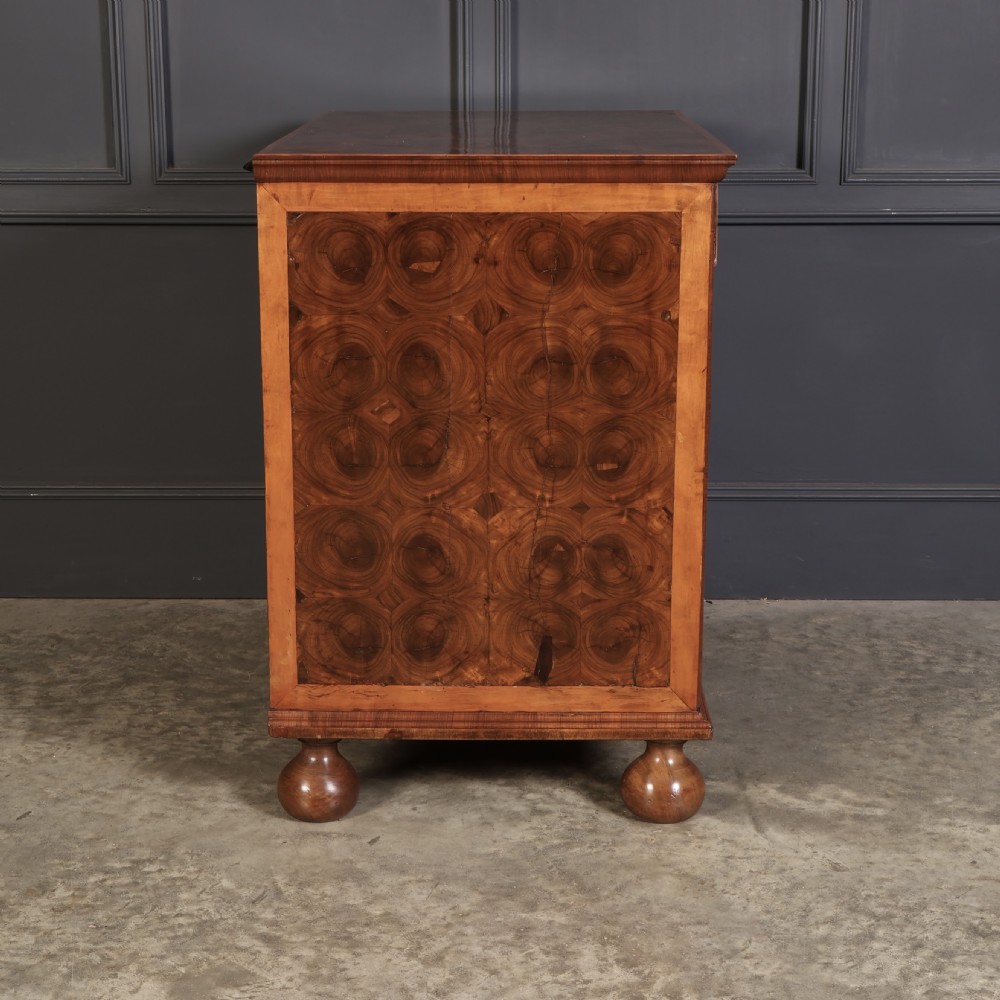A late 17th-century William and Mary walnut chest of drawers featuring oyster veneered drawer fronts, geometric crossbanding, engraved brass drop handles, and turned bun feet. View XI