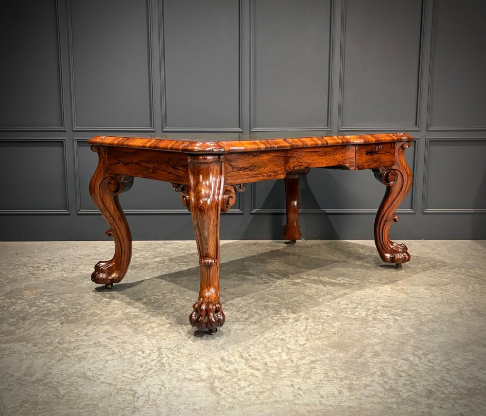 A William IV rosewood partners writing desk featuring a green leather inset top, carved serpentine aprons, and bold cabriole legs ending in carved feet. View II