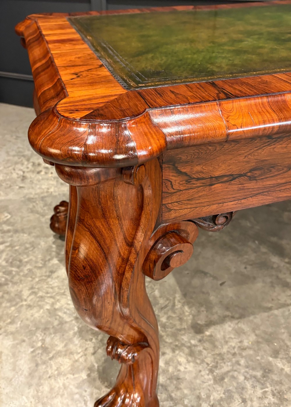 A William IV rosewood partners writing desk featuring a green leather inset top, carved serpentine aprons, and bold cabriole legs ending in carved feet. View V