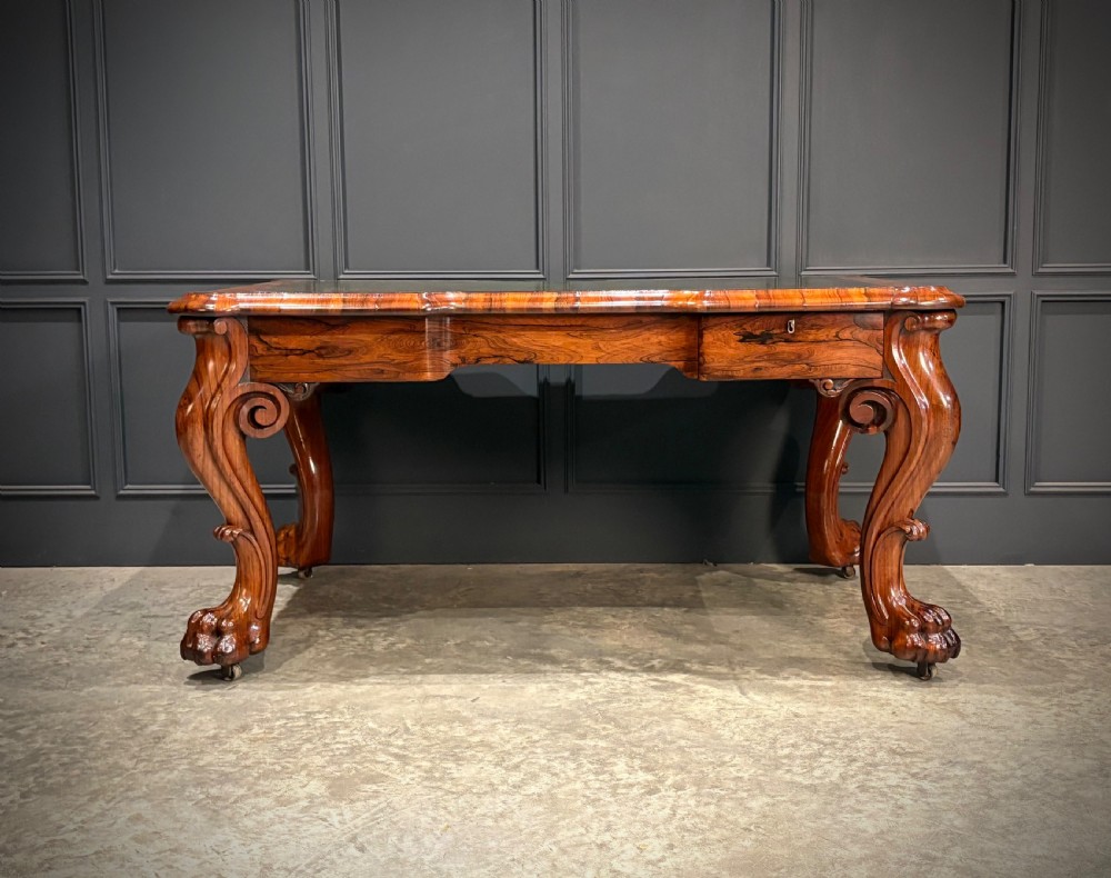 A William IV rosewood partners writing desk featuring a green leather inset top, carved serpentine aprons, and bold cabriole legs ending in carved feet. View VIII
