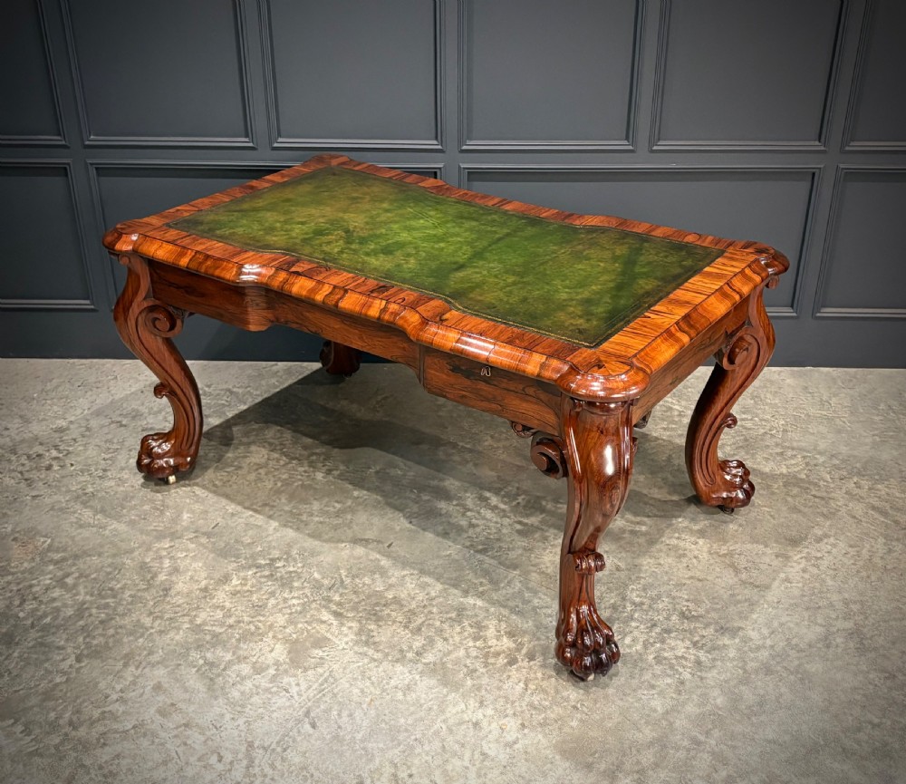 A William IV rosewood partners writing desk featuring a green leather inset top, carved serpentine aprons, and bold cabriole legs ending in carved feet. View IX
