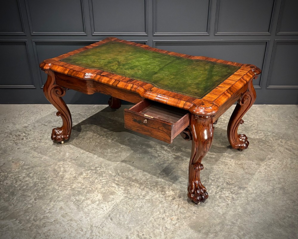 A William IV rosewood partners writing desk featuring a green leather inset top, carved serpentine aprons, and bold cabriole legs ending in carved feet. View X