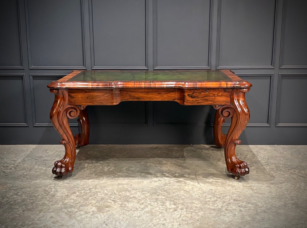 A William IV rosewood partners writing desk featuring a green leather inset top, carved serpentine aprons, and bold cabriole legs ending in carved feet. View XV