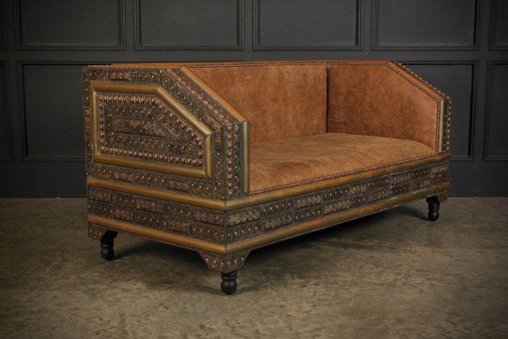 A three-piece Moroccan seating suite comprising a sofa and two armchairs upholstered in tan leather with brass studding and geometric metal trim. View V