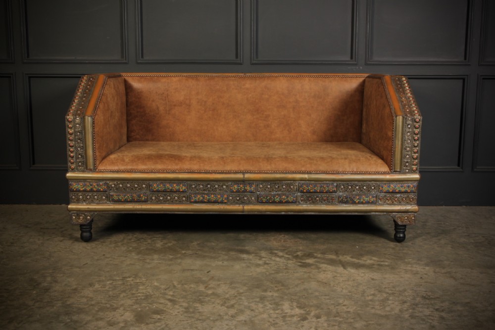 A three-piece Moroccan seating suite comprising a sofa and two armchairs upholstered in tan leather with brass studding and geometric metal trim. View II