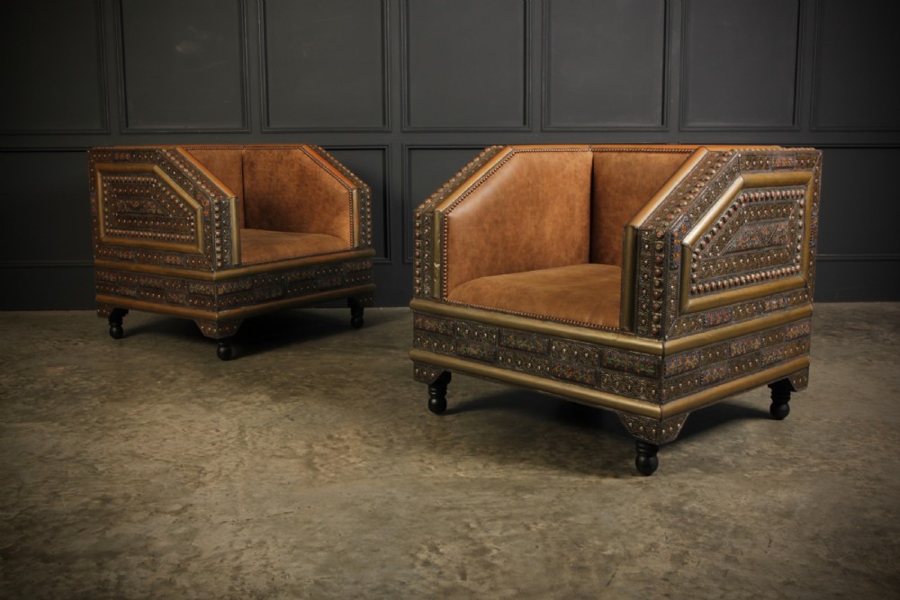 A three-piece Moroccan seating suite comprising a sofa and two armchairs upholstered in tan leather with brass studding and geometric metal trim. View VI