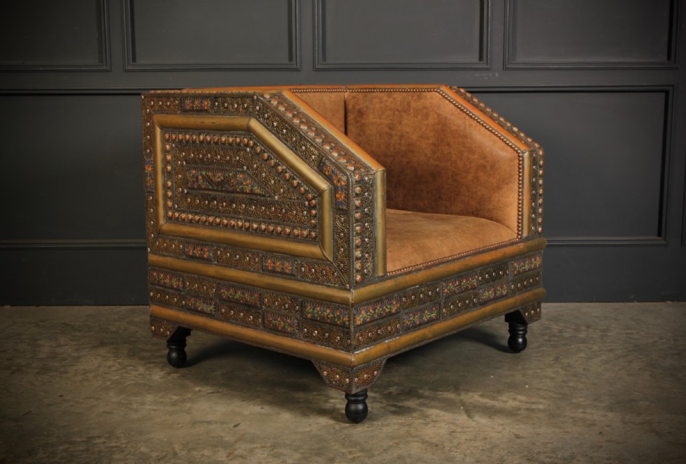 A three-piece Moroccan seating suite comprising a sofa and two armchairs upholstered in tan leather with brass studding and geometric metal trim. View VII
