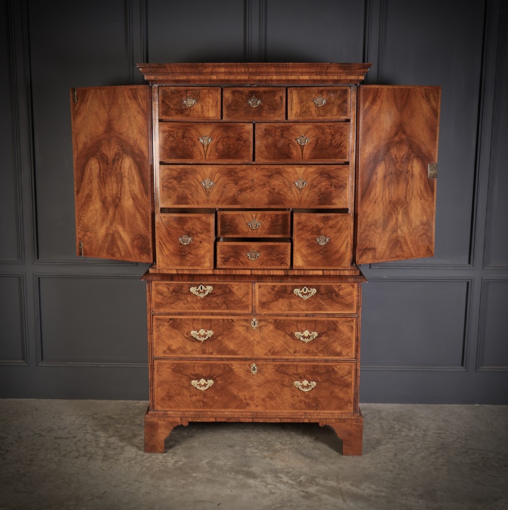 A two-part Queen Anne walnut cabinet on chest featuring upper cupboard doors with bookmatched timber grain and a lower chest with four drawers on bracket feet. View V