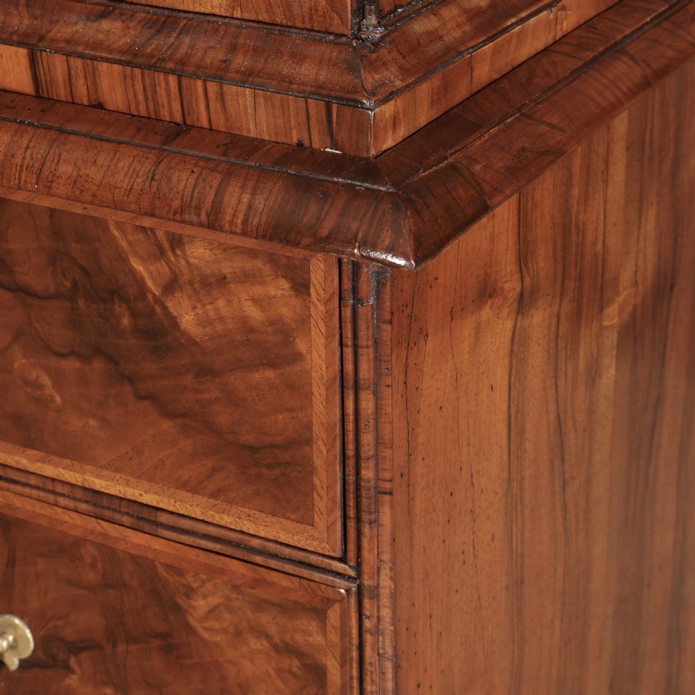 A two-part Queen Anne walnut cabinet on chest featuring upper cupboard doors with bookmatched timber grain and a lower chest with four drawers on bracket feet. View XI