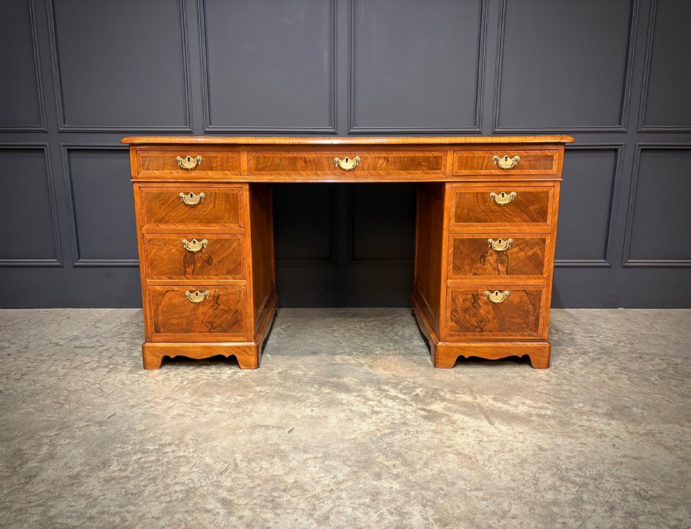 An antique burr walnut pedestal desk featuring inlaid feather-banded borders, brass drop handles, and multiple side drawers. View II