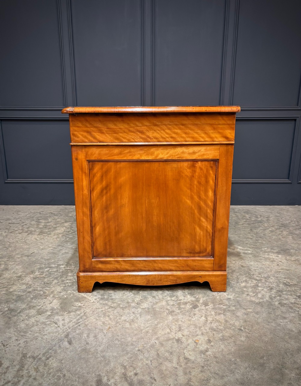 An antique burr walnut pedestal desk featuring inlaid feather-banded borders, brass drop handles, and multiple side drawers. View XII