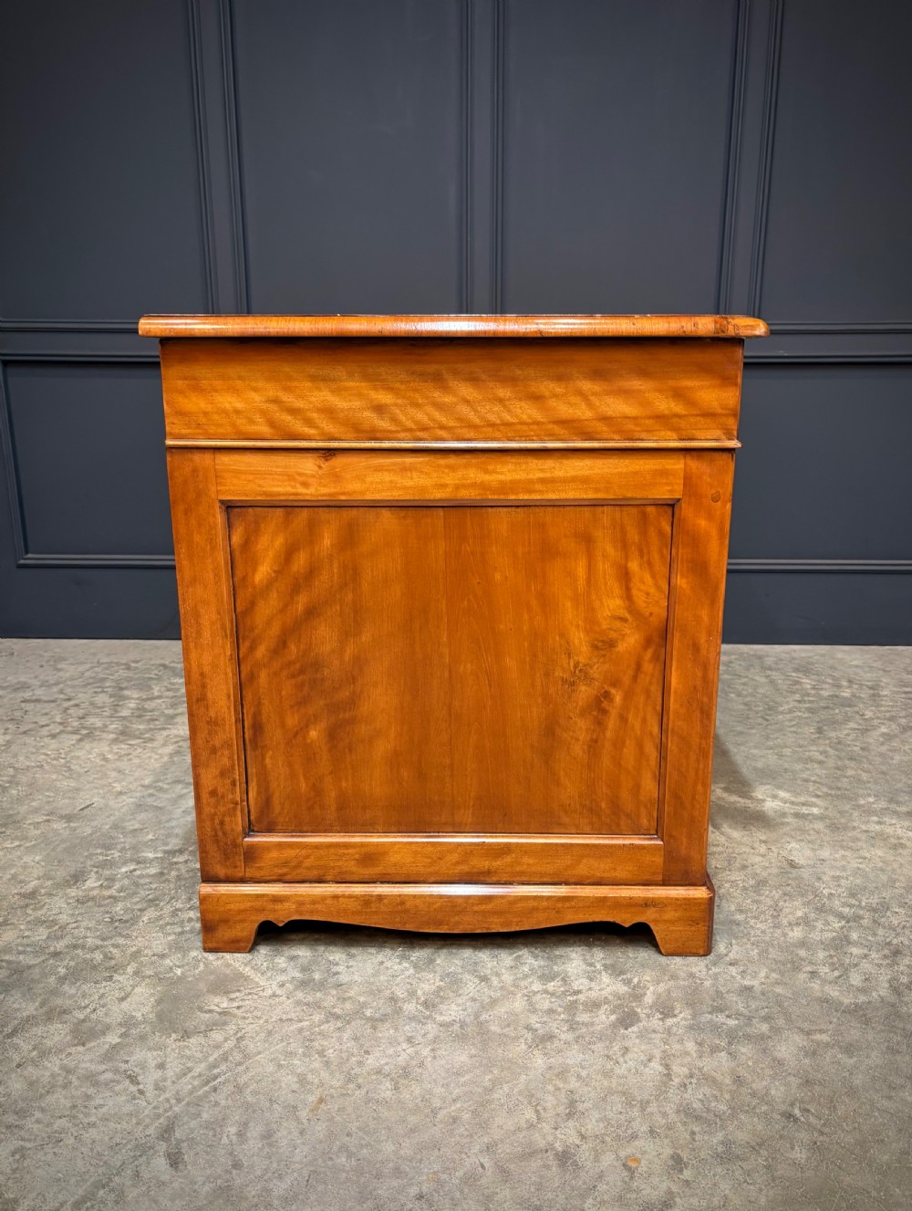 An antique burr walnut pedestal desk featuring inlaid feather-banded borders, brass drop handles, and multiple side drawers. View XIV