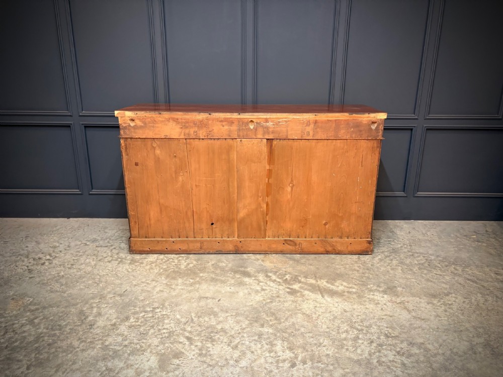 A Victorian mahogany sideboard featuring three flame mahogany veneer arched panel doors and concealed frieze drawers set on a plinth base. View XI