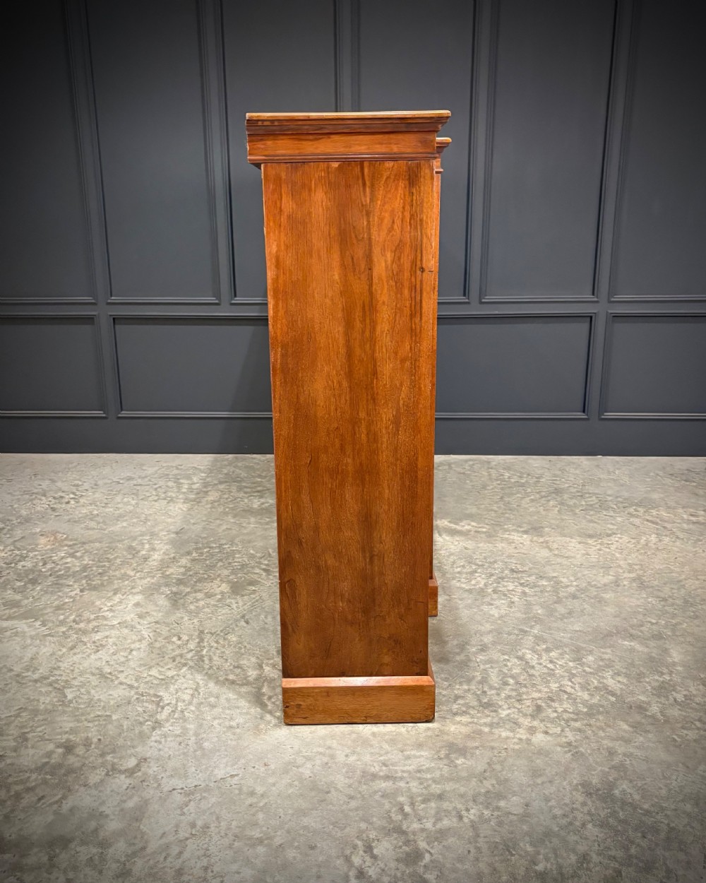 A low breakfront walnut bookcase featuring a central two-door cupboard flanked by open shelves and top drawers with brass handles. View XIII