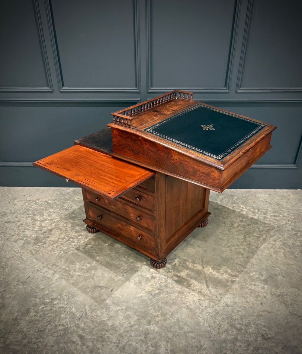 A 19th-century rosewood Davenport desk featuring a sloped writing top inset with dark green tooled leather, a spindled gallery rail, and stacked drawers. View XXII