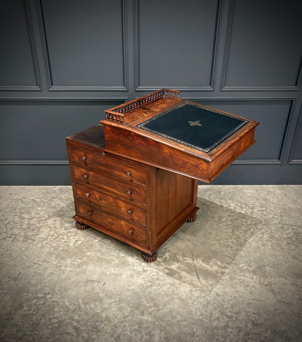 A 19th-century rosewood Davenport desk featuring a sloped writing top inset with dark green tooled leather, a spindled gallery rail, and stacked drawers. View XXIII