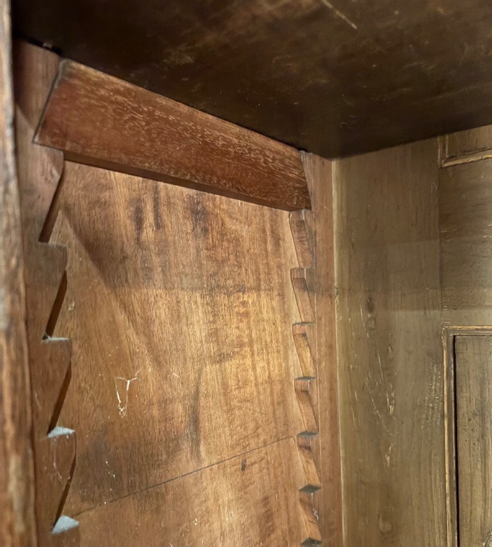 An early Victorian warm brown oak breakfront bookcase featuring glazed upper doors with arched tops, carved corbel accents, and a lower cabinet base. View V