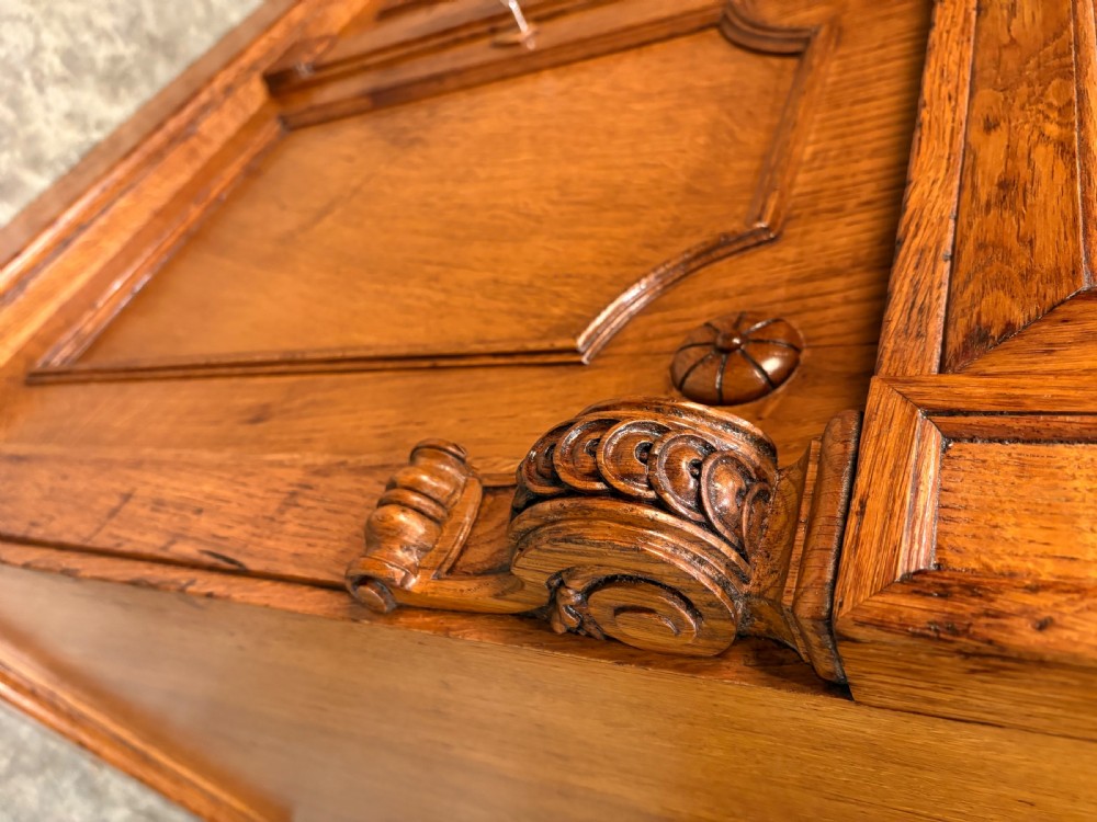 An early Victorian warm brown oak breakfront bookcase featuring glazed upper doors with arched tops, carved corbel accents, and a lower cabinet base. View XVI