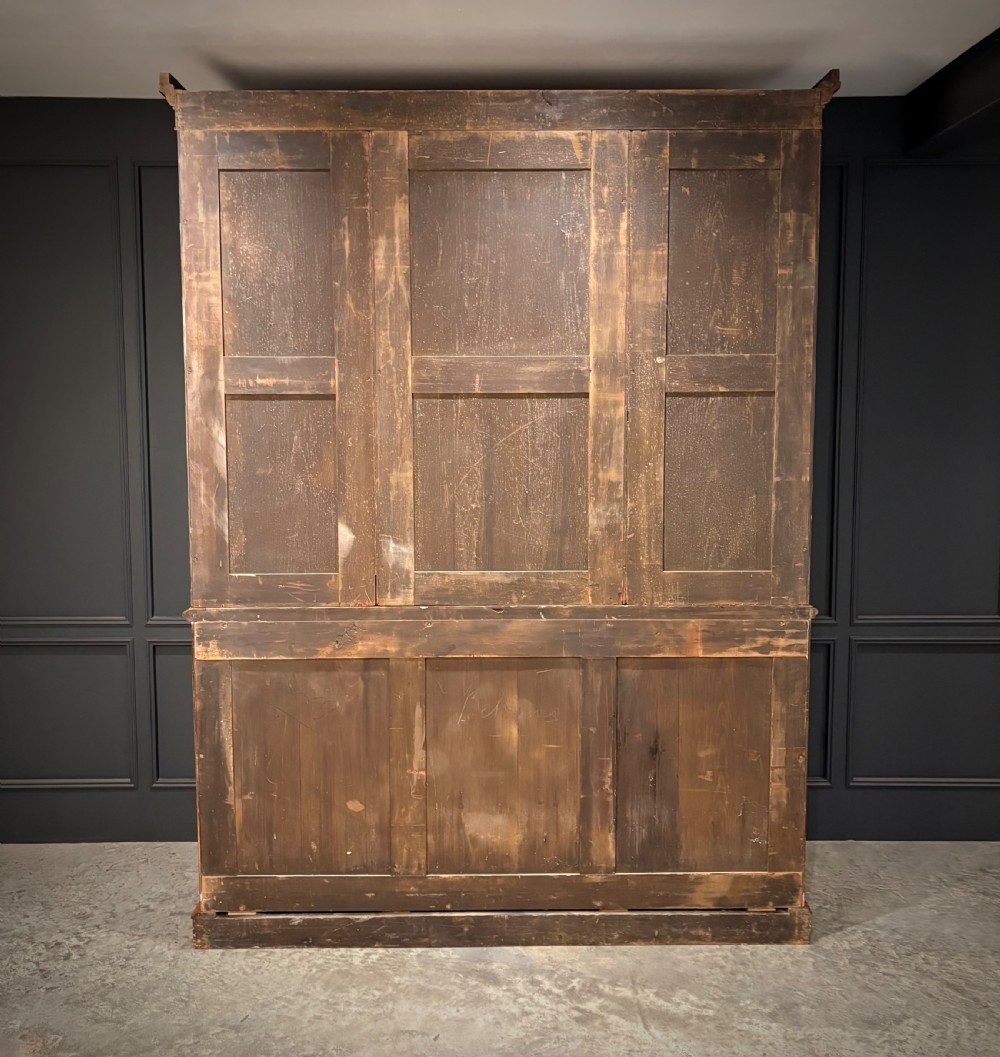 An early Victorian warm brown oak breakfront bookcase featuring glazed upper doors with arched tops, carved corbel accents, and a lower cabinet base. View XVIII
