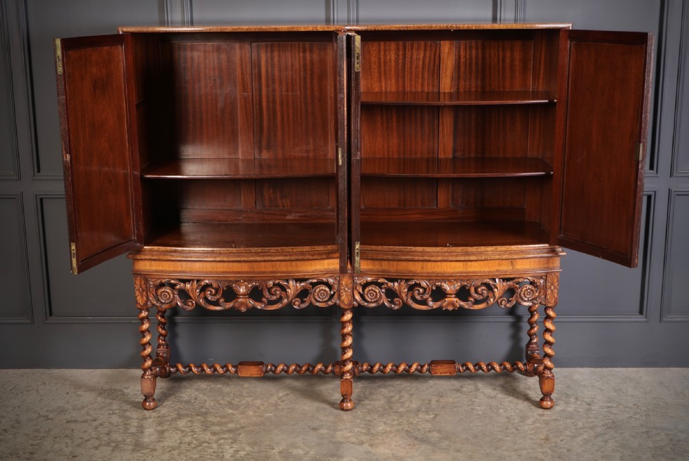 A double bow-front burr walnut cocktail cabinet featuring carved scrollwork on the lower apron, supported by six barley twist legs joined by stretchers. View VII