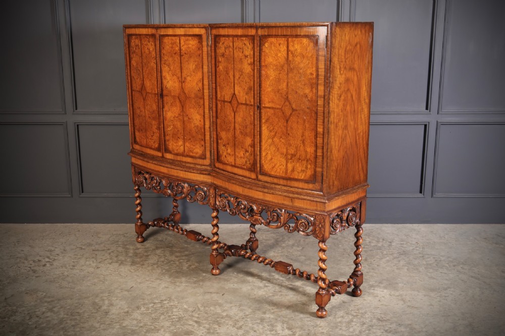 A double bow-front burr walnut cocktail cabinet featuring carved scrollwork on the lower apron, supported by six barley twist legs joined by stretchers. View VIII