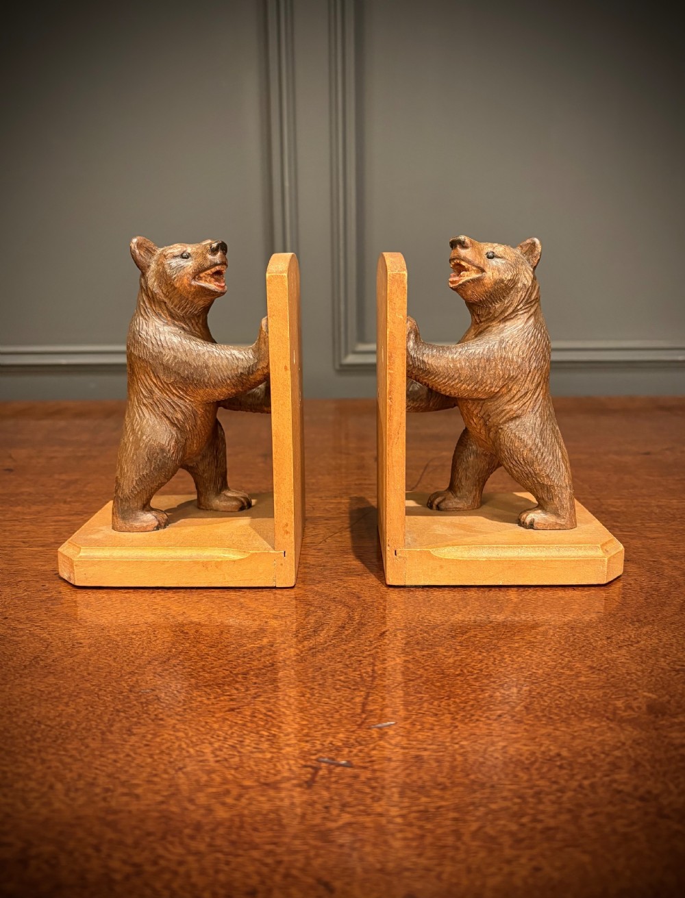 A pair of hand-carved wooden bookends depicting standing bears with open mouths pushing against vertical wooden supports.