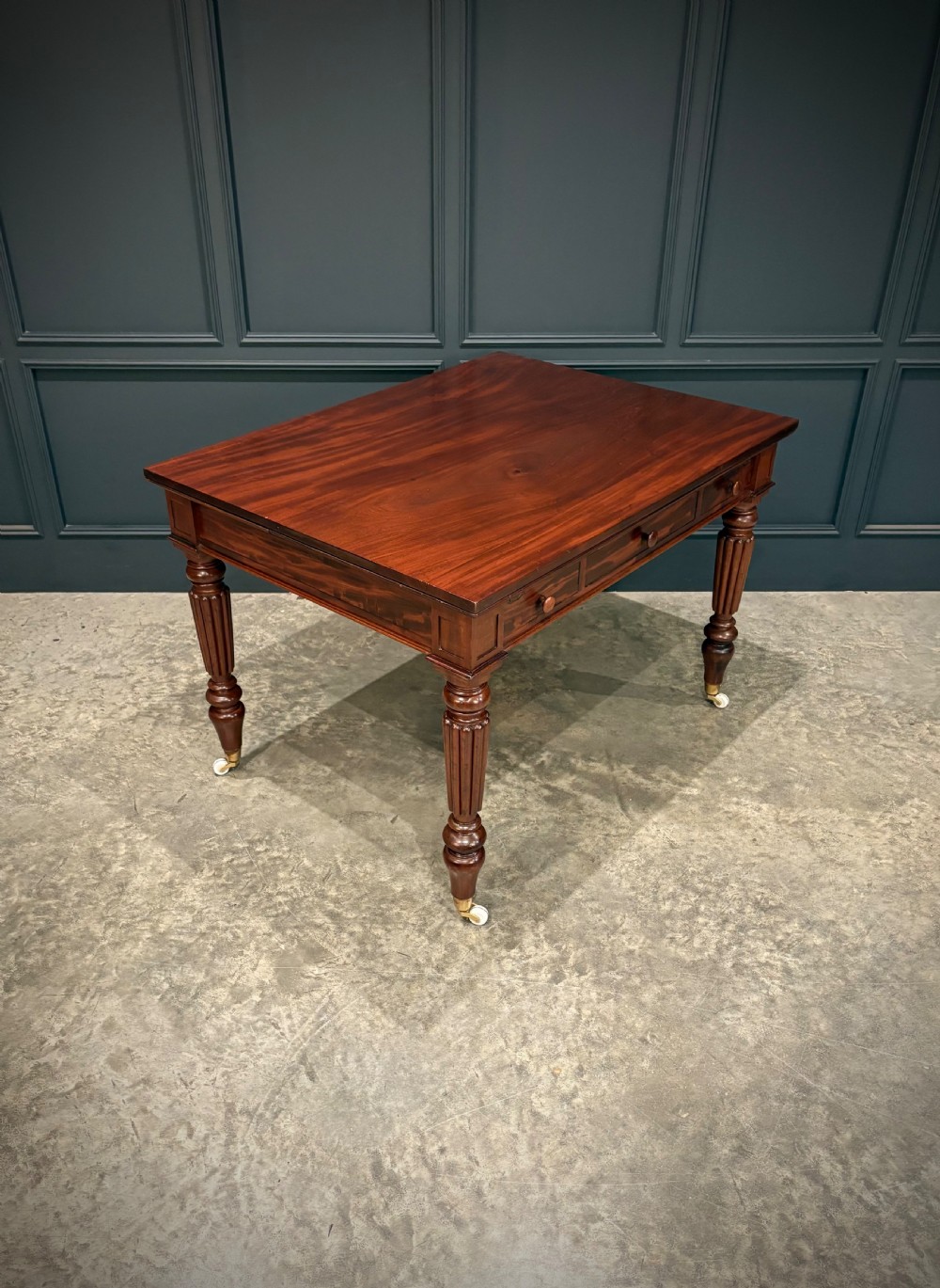 Victorian mahogany writing table with a polished flat top, frieze drawers with wooden turned knobs, and reeded turned legs on brass castors. View IV