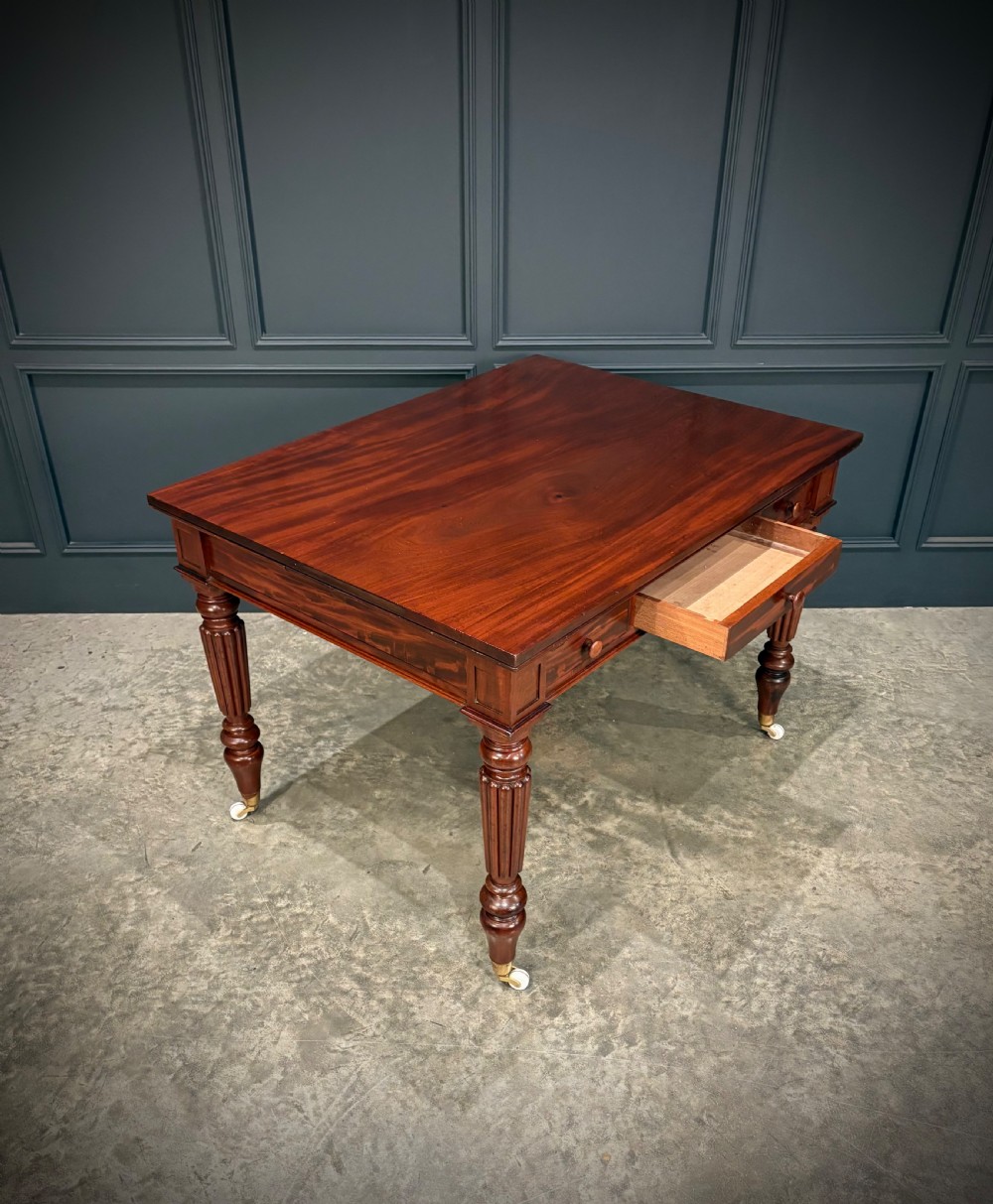 Victorian mahogany writing table with a polished flat top, frieze drawers with wooden turned knobs, and reeded turned legs on brass castors. View III
