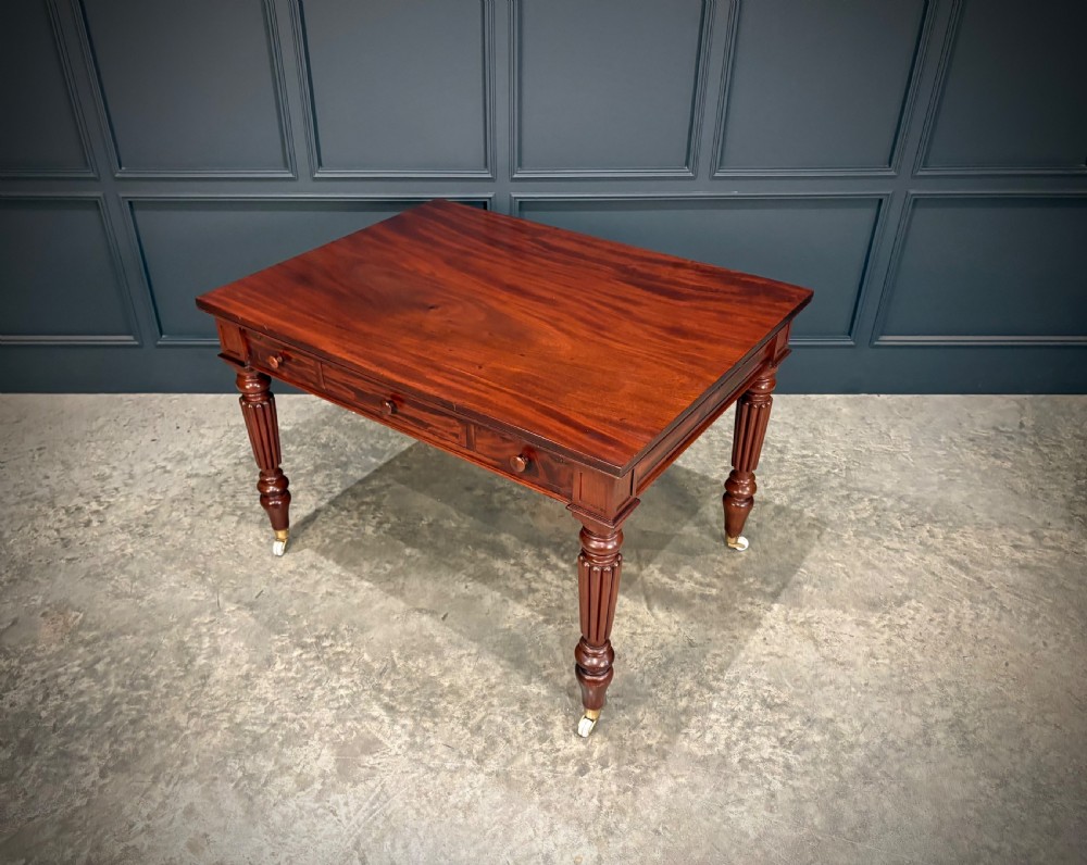 Victorian mahogany writing table with a polished flat top, frieze drawers with wooden turned knobs, and reeded turned legs on brass castors. View V