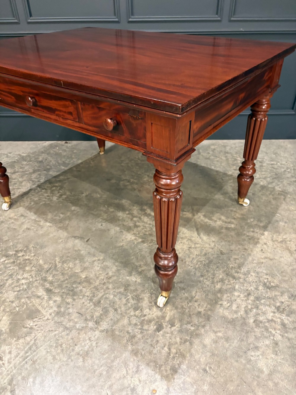 Victorian mahogany writing table with a polished flat top, frieze drawers with wooden turned knobs, and reeded turned legs on brass castors. View VII