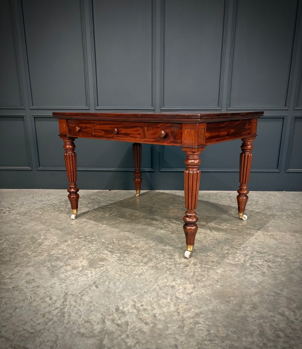 Victorian mahogany writing table with a polished flat top, frieze drawers with wooden turned knobs, and reeded turned legs on brass castors. View VIII