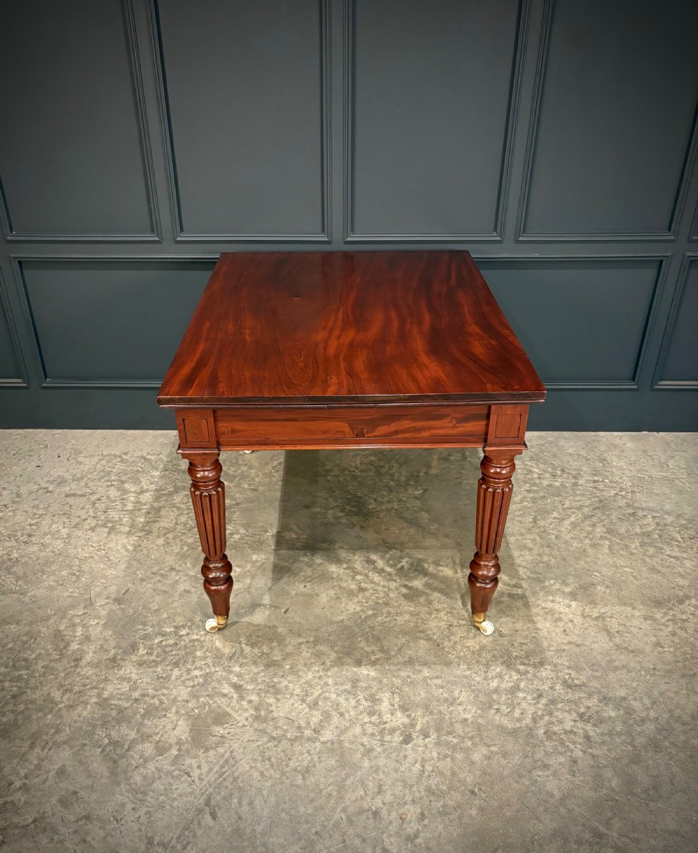 Victorian mahogany writing table with a polished flat top, frieze drawers with wooden turned knobs, and reeded turned legs on brass castors. View X