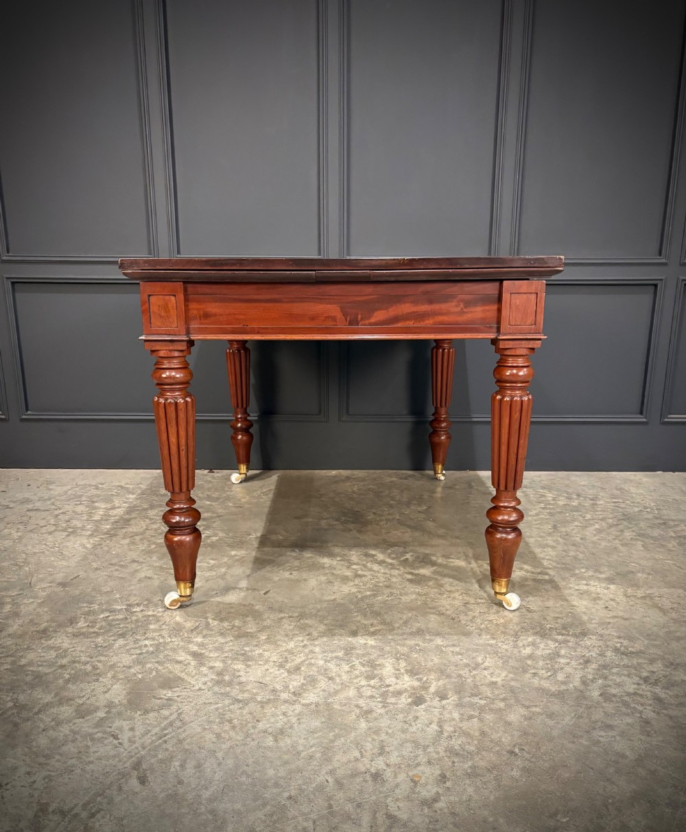 Victorian mahogany writing table with a polished flat top, frieze drawers with wooden turned knobs, and reeded turned legs on brass castors. View XI