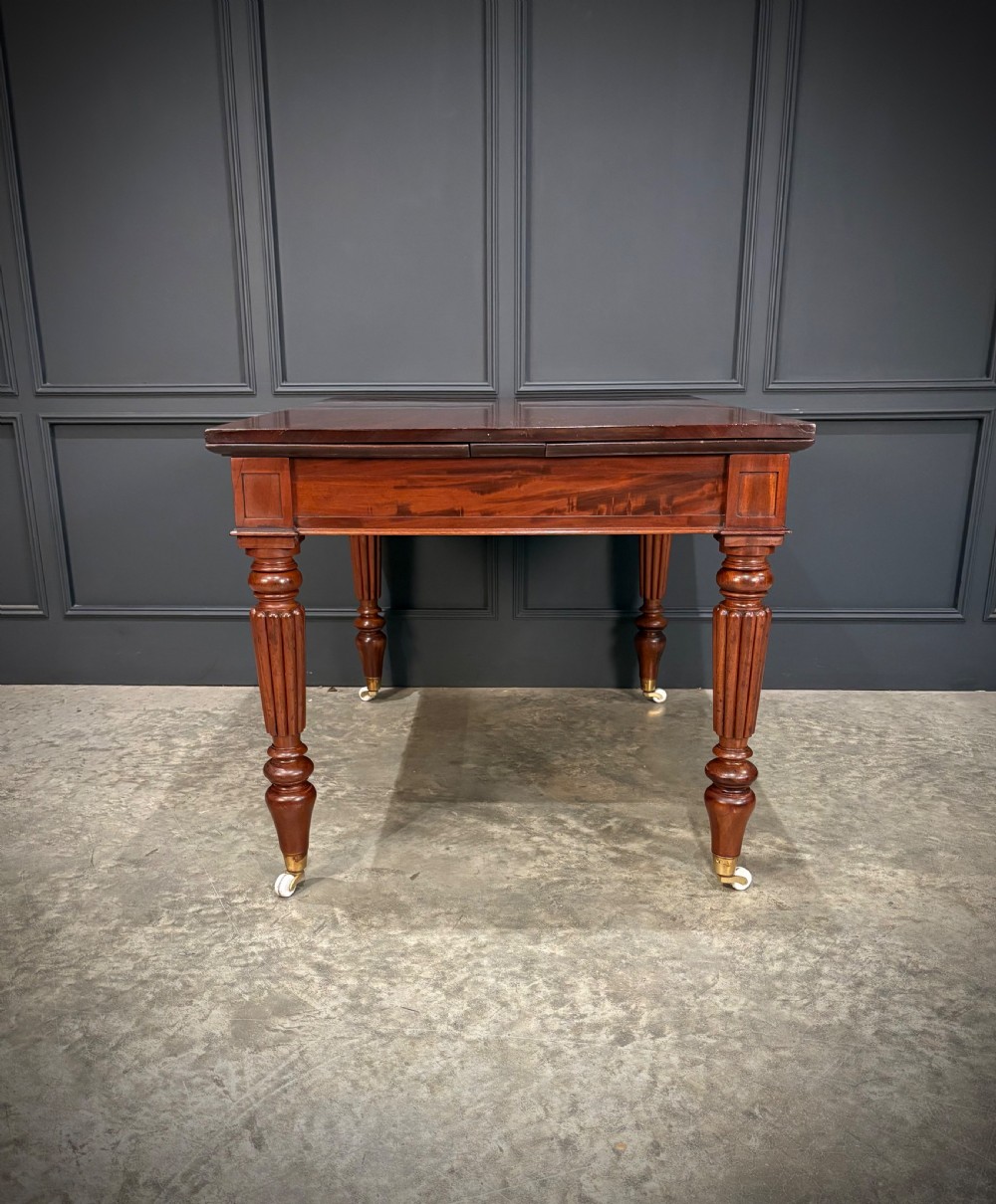 Victorian mahogany writing table with a polished flat top, frieze drawers with wooden turned knobs, and reeded turned legs on brass castors. View XIV