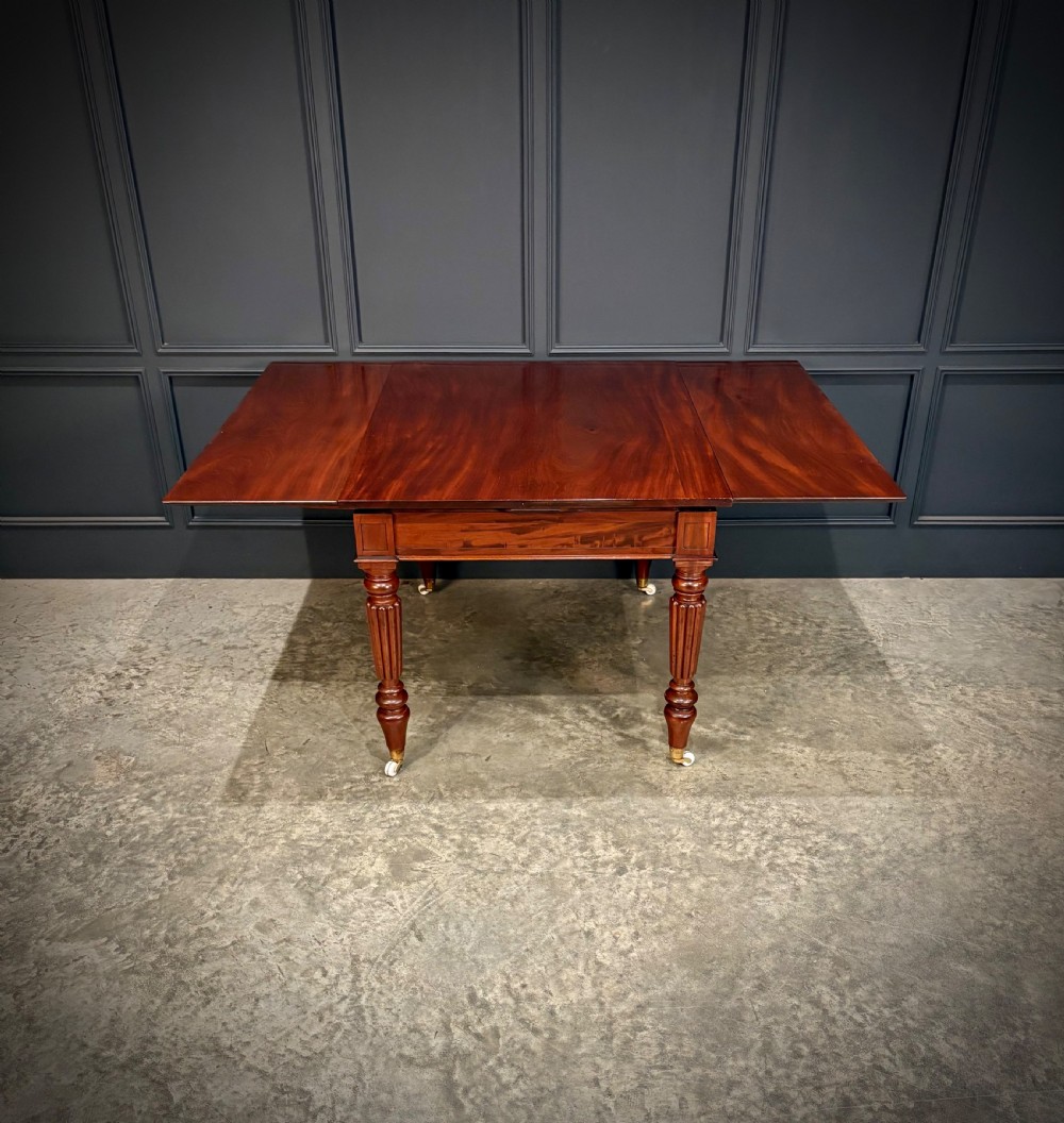 Victorian mahogany writing table with a polished flat top, frieze drawers with wooden turned knobs, and reeded turned legs on brass castors. View XV