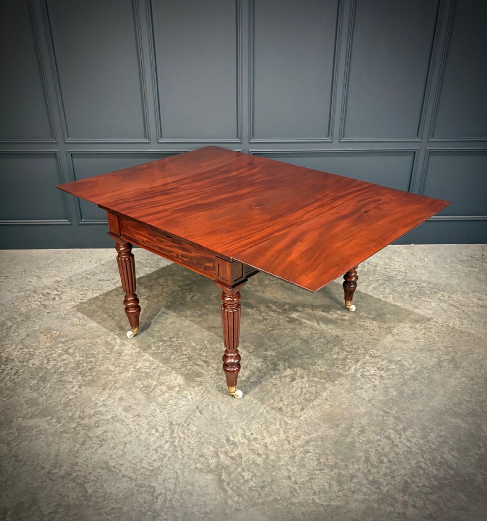 Victorian mahogany writing table with a polished flat top, frieze drawers with wooden turned knobs, and reeded turned legs on brass castors. View XVI