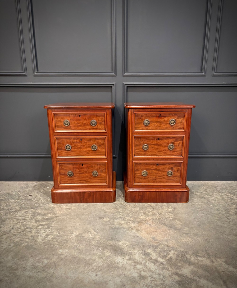 A pair of Victorian mahogany bedside chests, each featuring three drawers with brass drop ring handles on a solid plinth base. View III
