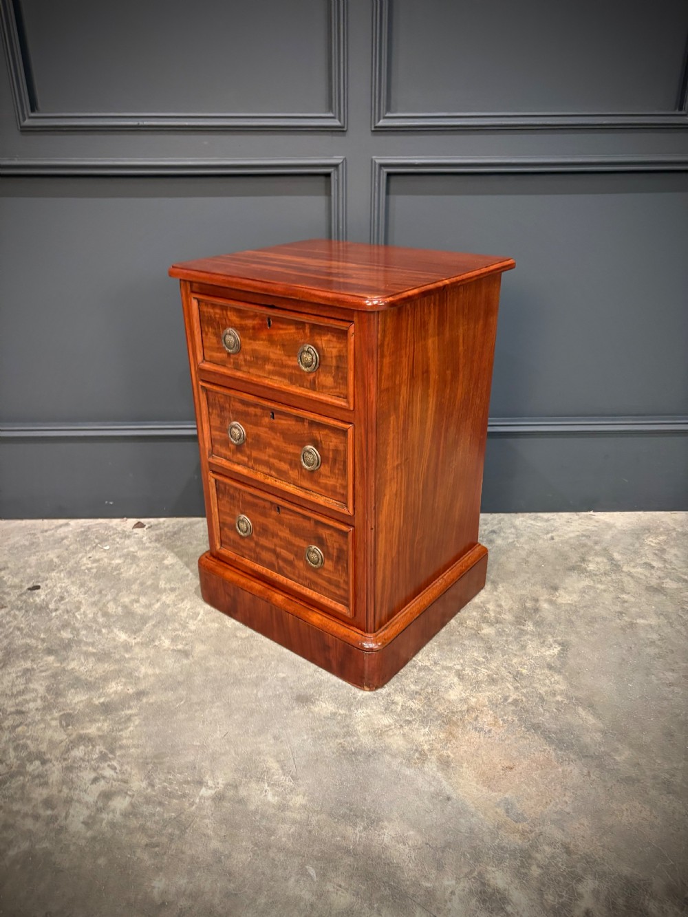 A pair of Victorian mahogany bedside chests, each featuring three drawers with brass drop ring handles on a solid plinth base. View VIII