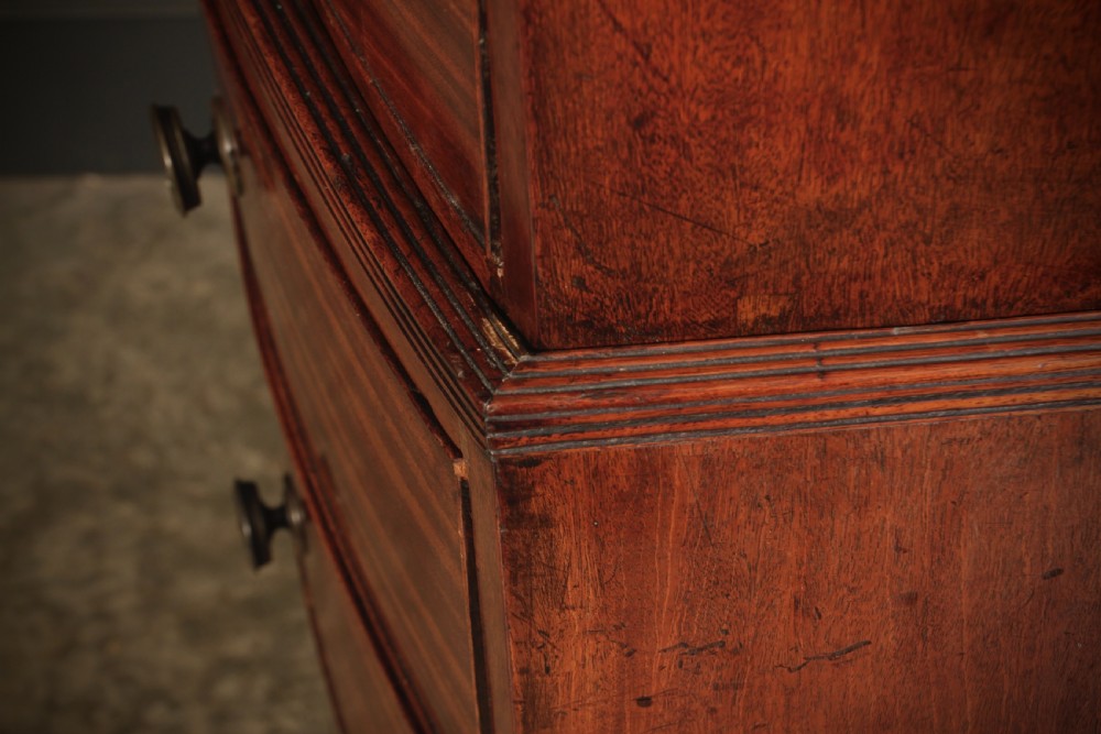 A tall Regency mahogany bowfront chest on chest featuring a curved front face with stacked drawers and splayed bracket feet. View VIII
