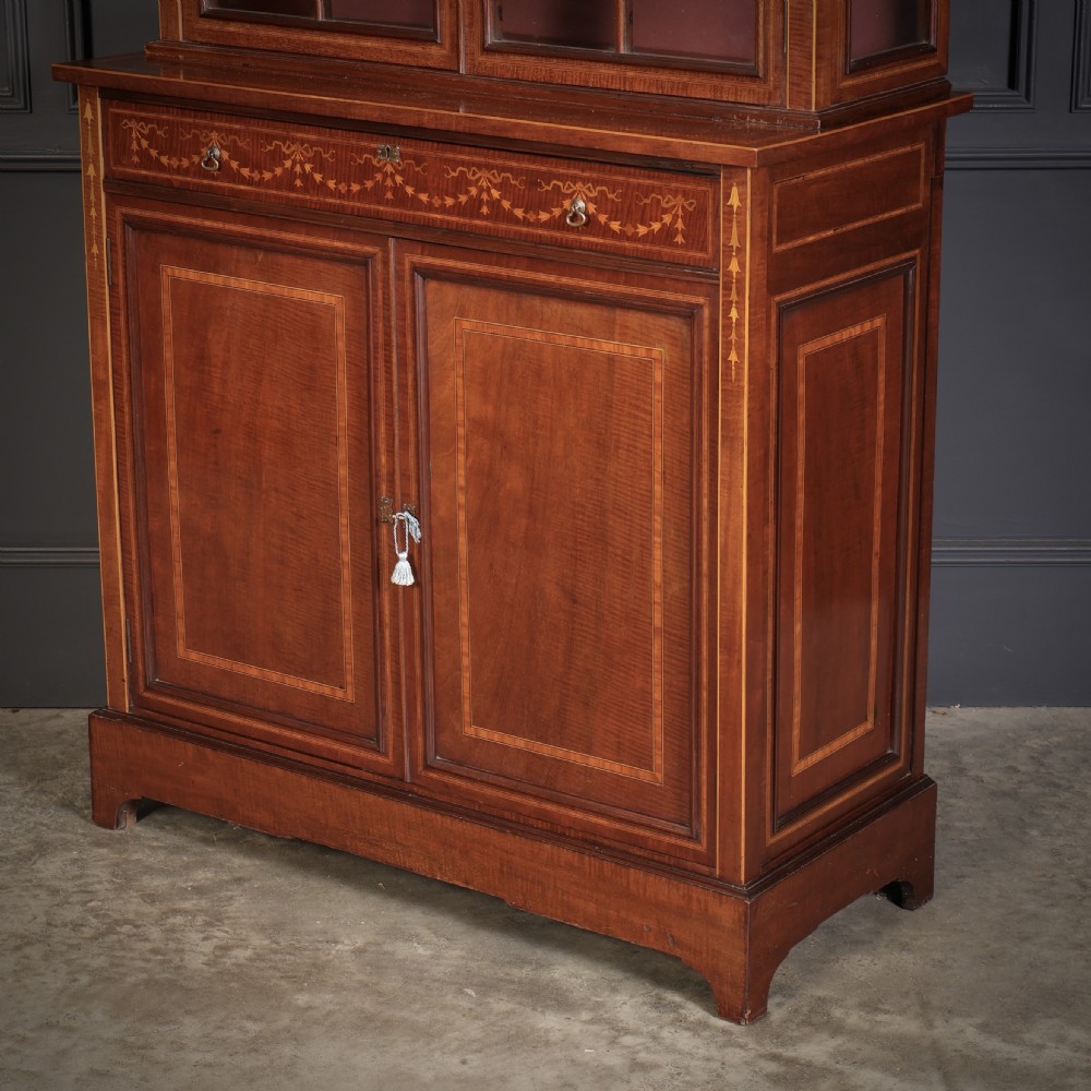 A tall mahogany glazed cabinet bookcase featuring marquetry inlay, astragal glazed doors, a swan-neck pediment, and a two-door lower cupboard. View III