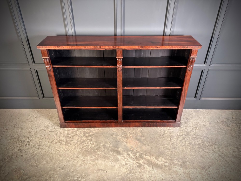 A low Victorian open bookcase made from dark rosewood with two bays of adjustable shelves and carved corbels. View IV