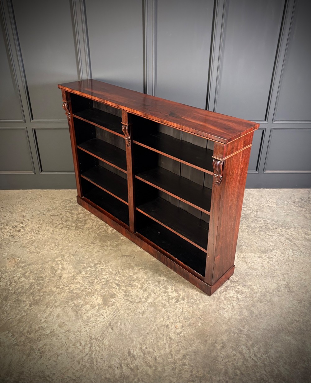 A low Victorian open bookcase made from dark rosewood with two bays of adjustable shelves and carved corbels. View V