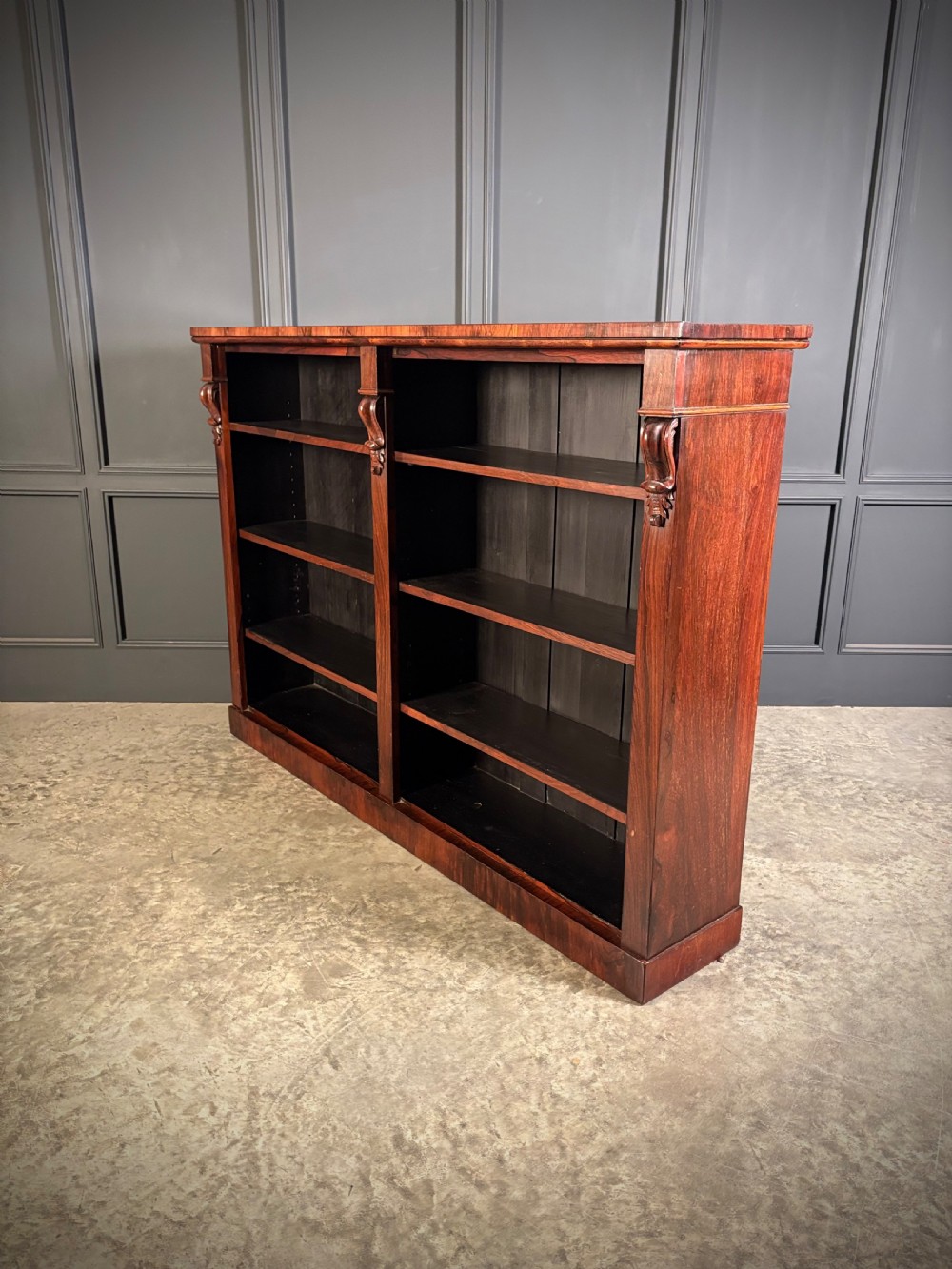 A low Victorian open bookcase made from dark rosewood with two bays of adjustable shelves and carved corbels. View VI