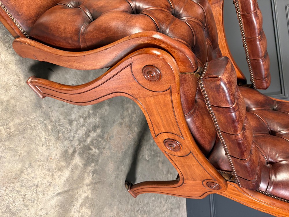 A Regency mahogany reclining armchair featuring button-tufted brown leather upholstery, padded armrests, an adjustable footrest, brass castors, and carved timber details. View VIII