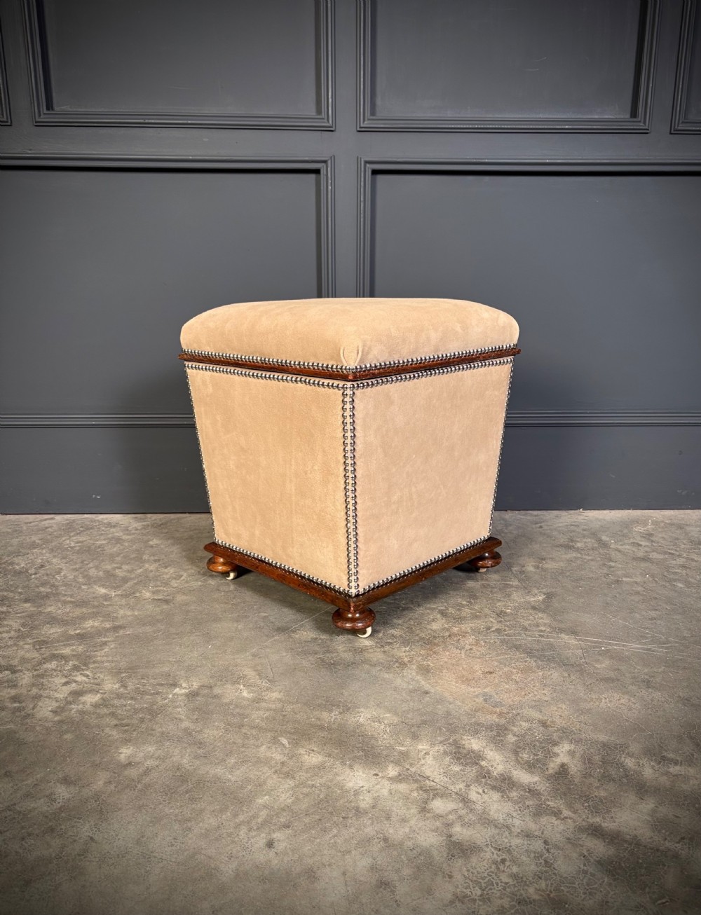 A pair of square Regency style ottomans upholstered in beige fabric with brass stud trimming, raised on short mahogany legs with castors. View VII